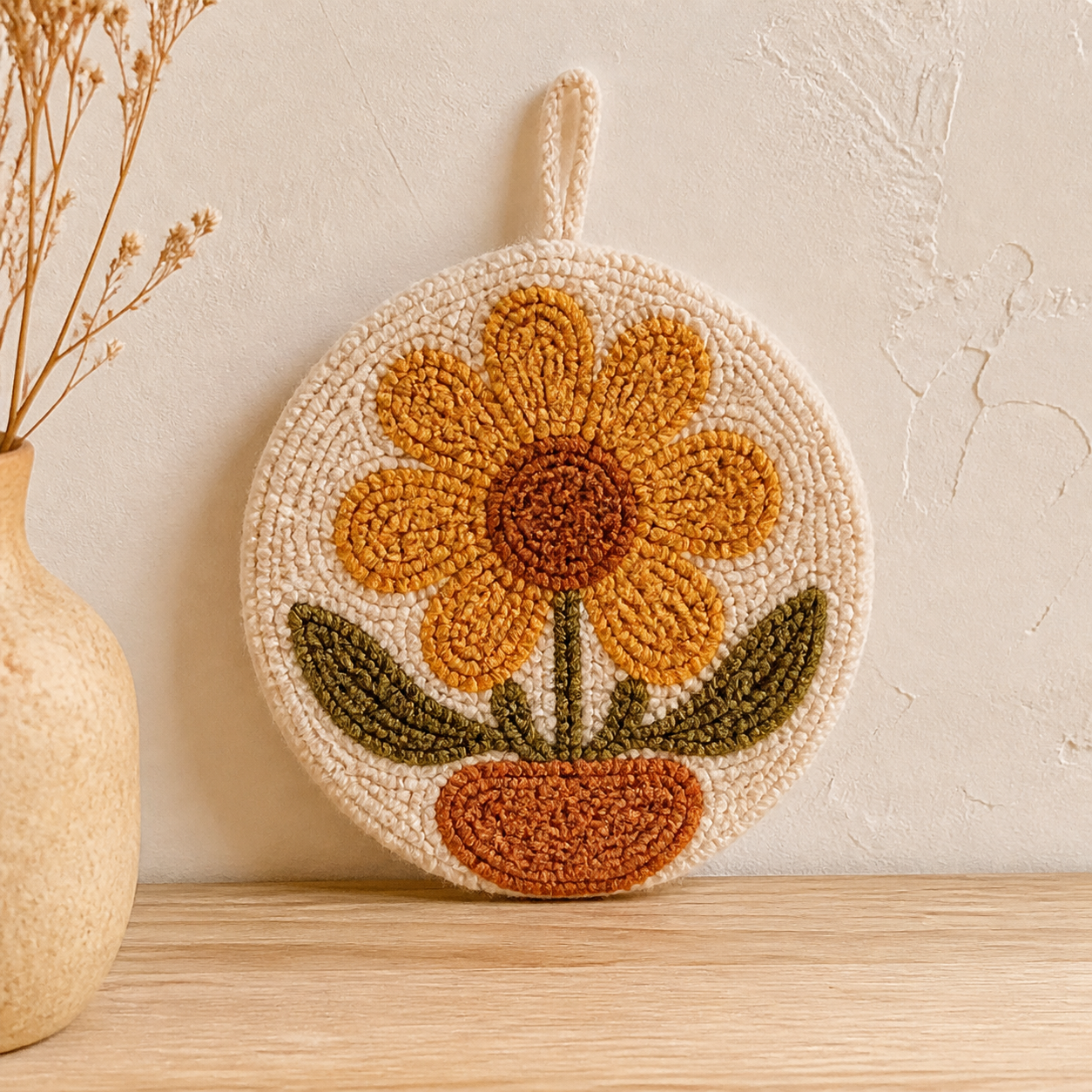 Fictional handmade punch-needle wall hanging with a marigold flower